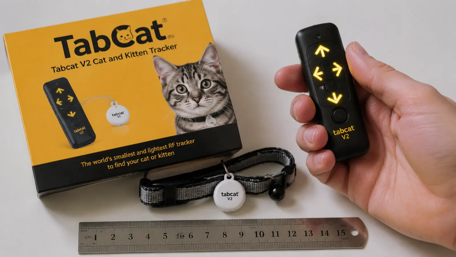 Cat collar with a Tabcat V2 tag next to a ruler showing the tag is roughly the size of a large coin